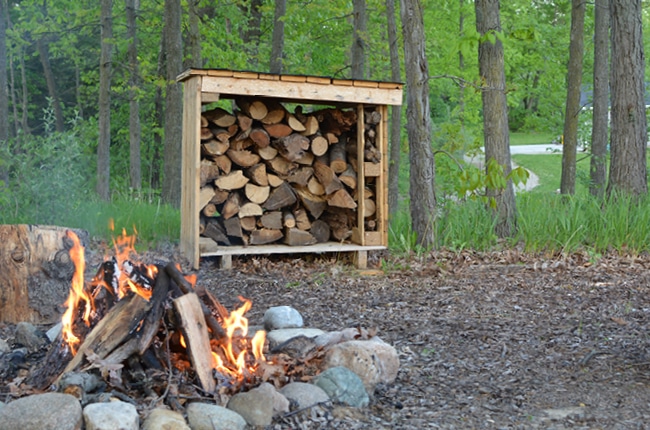 Make your own firewood storage using pallets to keep wood dry for your next family bonfire!