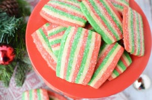 A red cake stand topped with holiday colored slice and bake cookie