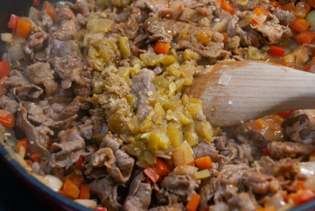 Adding green chilis to skillet