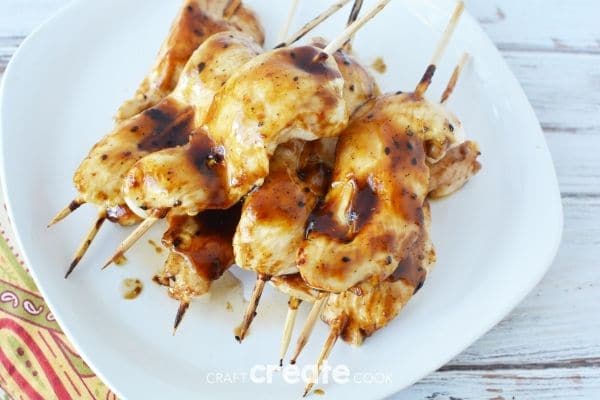 Chicken with sauce on skewers on white plate