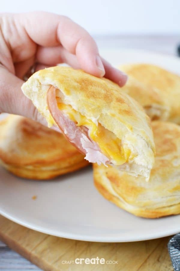Hand holding biscuit with ham and cheese inside