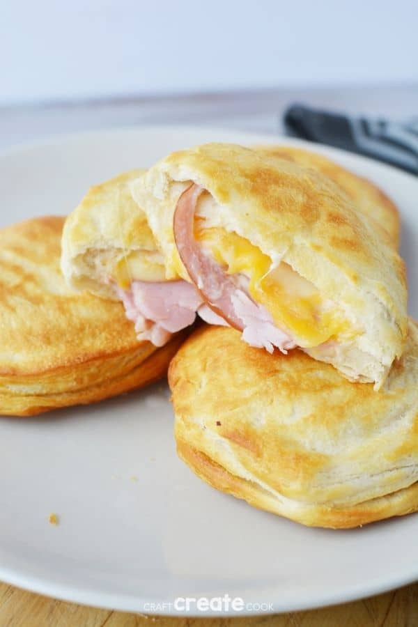 Ham and cheese biscuit sandwiches stacked on a white plate